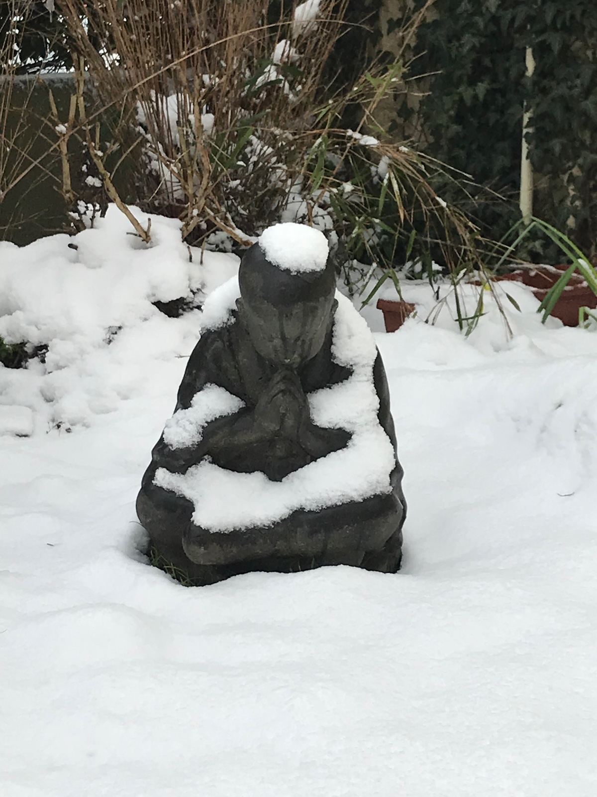 Petite statue de bouddha assise dans la neige au milieu du jardin