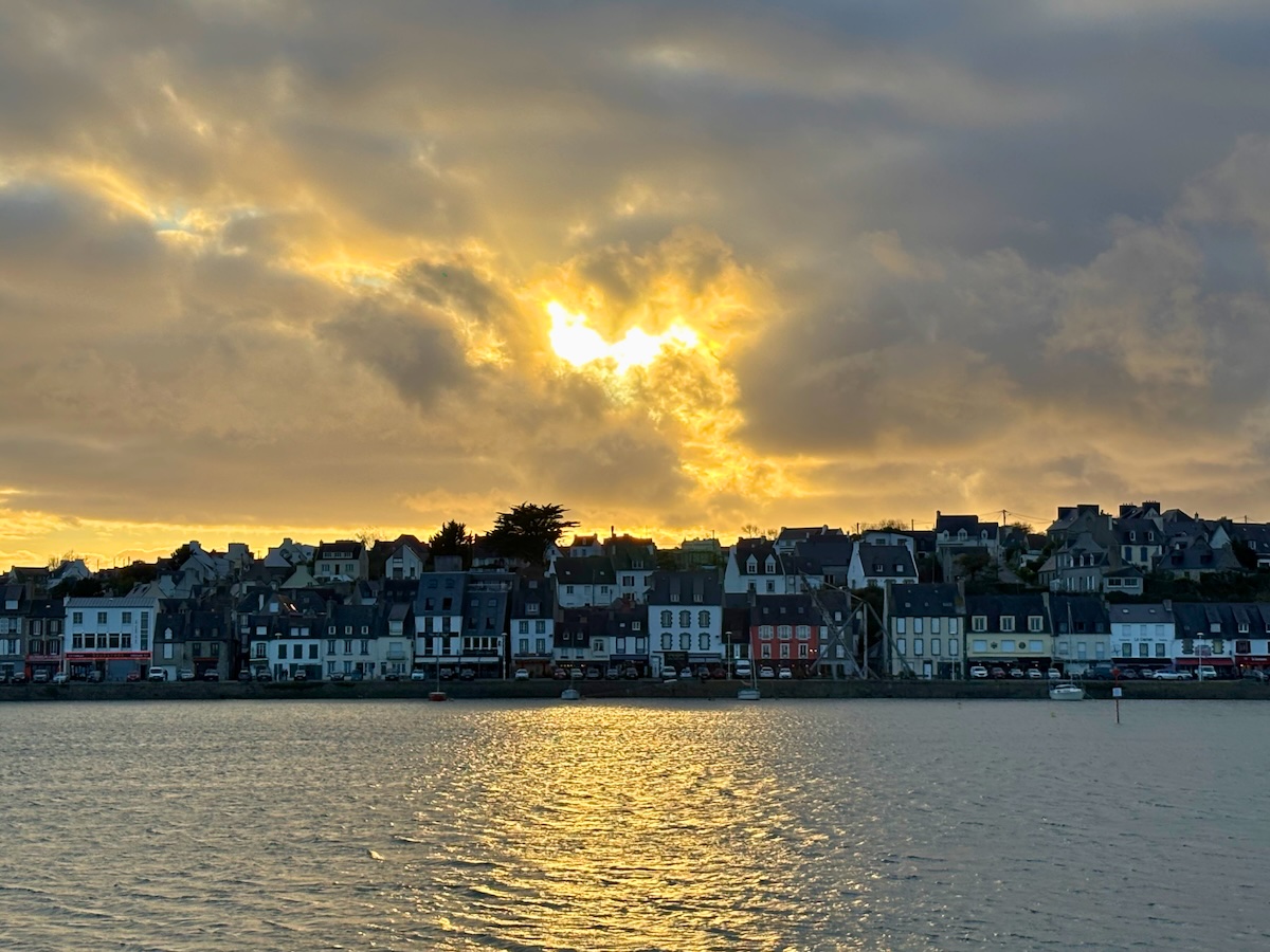 Ciel doré au-dessus des maisons colorées de Camaret-sur-Mer au coucher du soleil.
