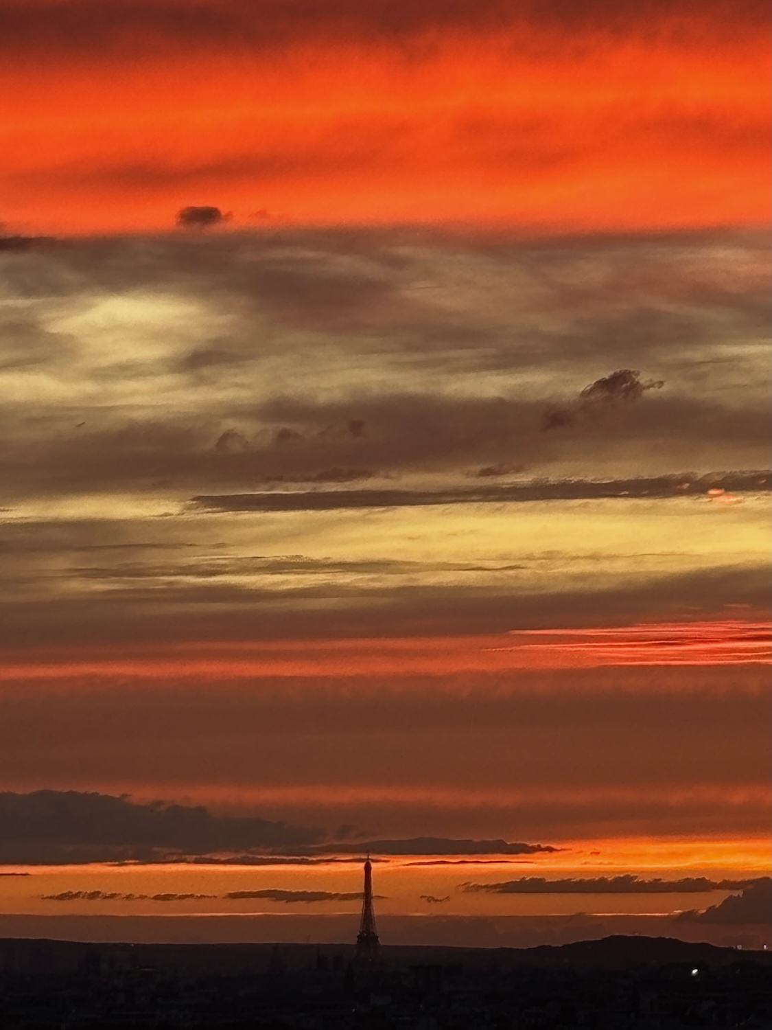 Coucher de soleil spectaculaire à Paris, dominé par des nuages rougeoyants et la silhouette de la tour Eiffel