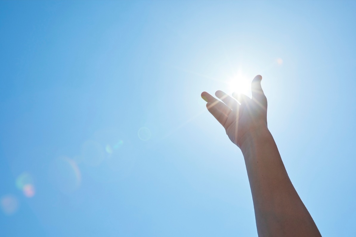 Main levée vers le soleil dans un ciel bleu lumineux symbolisant la réussite