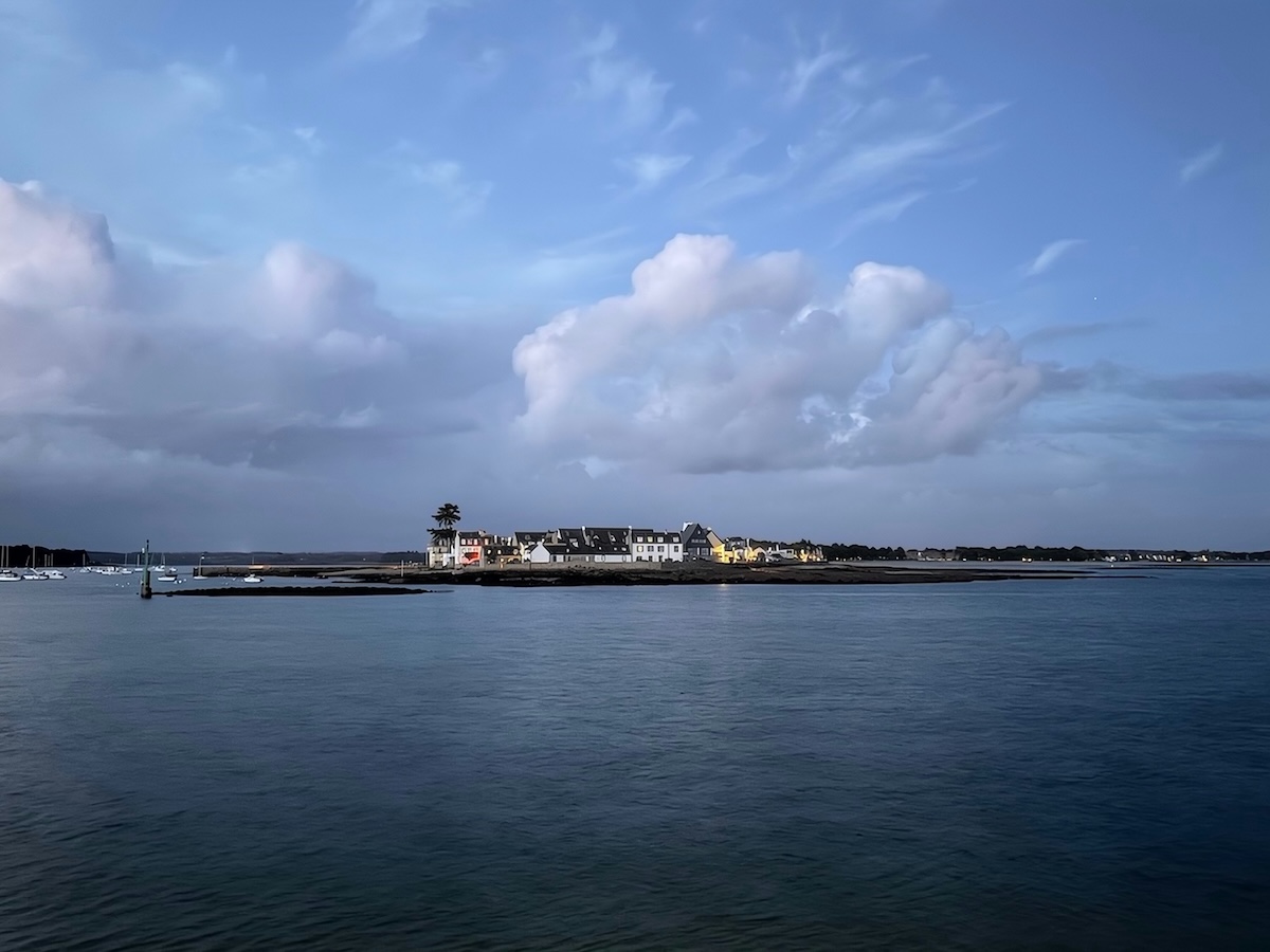 Vue sur l’Île-Tudy depuis la mer, sous un ciel chargé de nuages